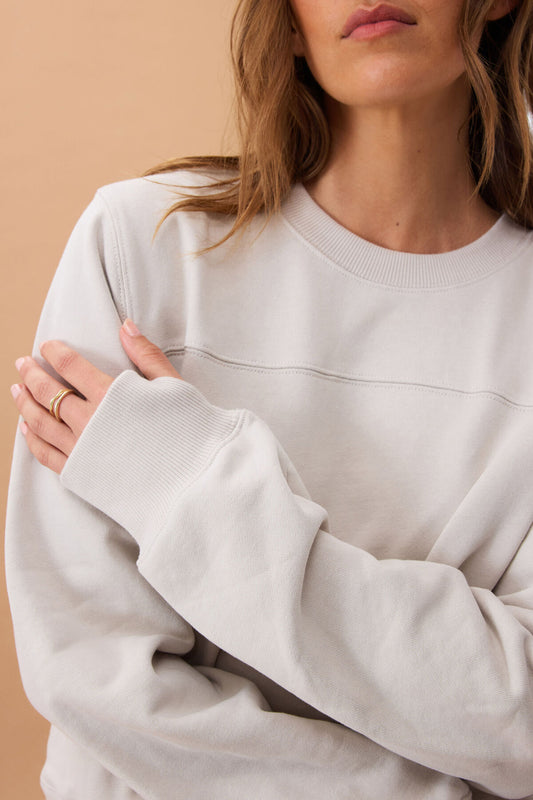 Person wearing an almond coloured sweatshirt against a beige background